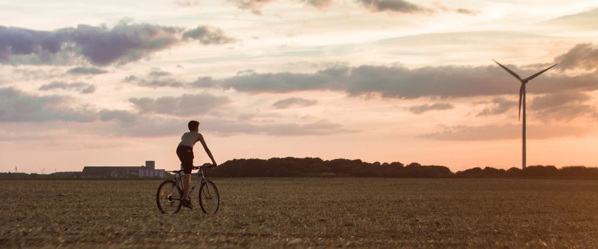 Junge fährt beim Sonnenuntergang auf dem Feld Fahrrad