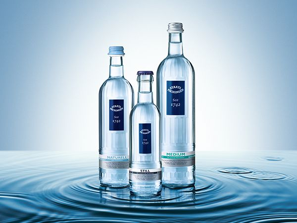 Drei Wasserflaschen und in Pfütze vor blauem Hintergrund