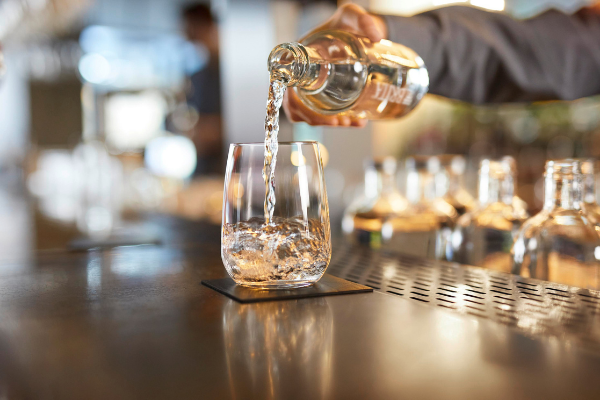 Menschenhand schenkt ein Glas Wasser ein