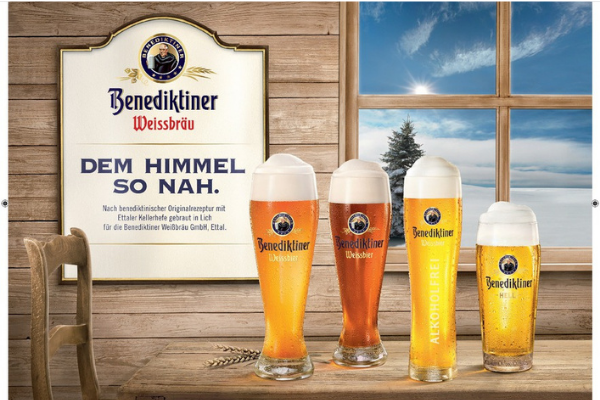 Vier Benedikter Biergläser mit Werbeschild vor Holzwand