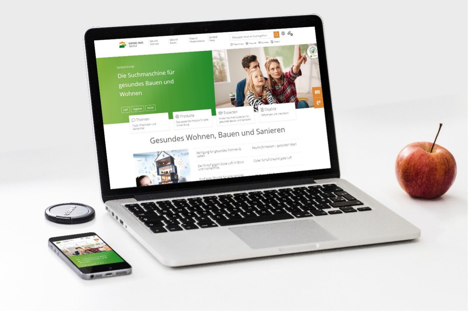PC mit Handy und Apfel auf weißem Hintergrund
