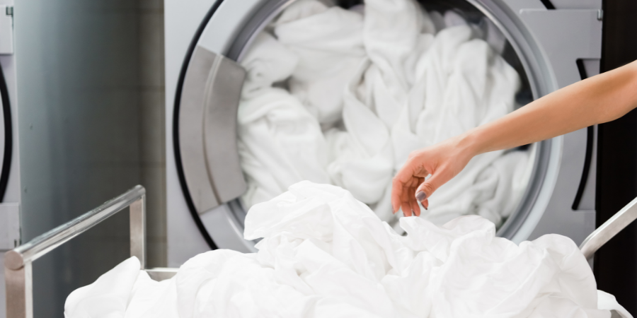 Haufen weißer Wäsche vor voller Waschmaschine
