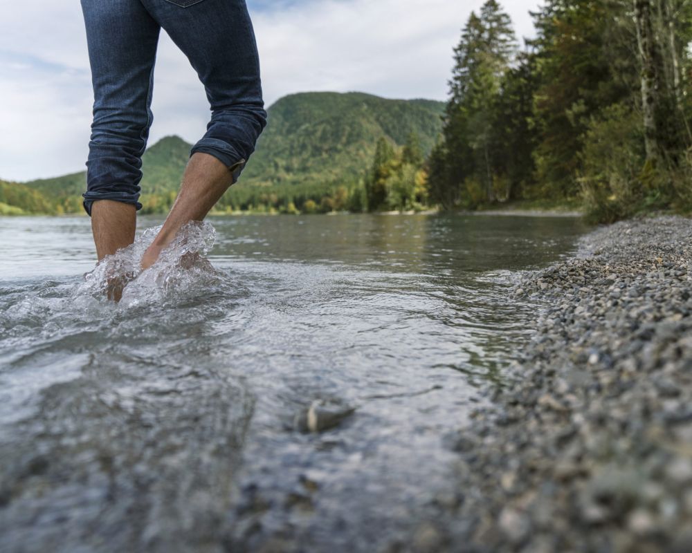 Füße waten durch Fluss