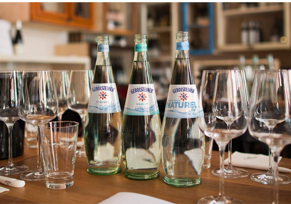 Einige Gerolsteiner Flaschen und Gläser stehen auf Holztisch in Restaurant