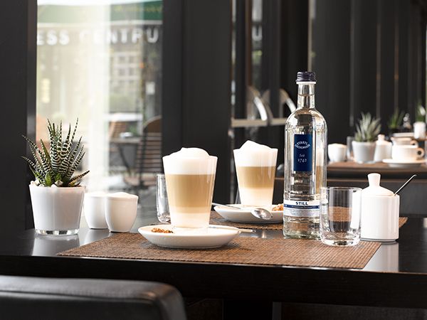 Latte Macchiato Gläser und Wasserflasche auf Tisch in Café