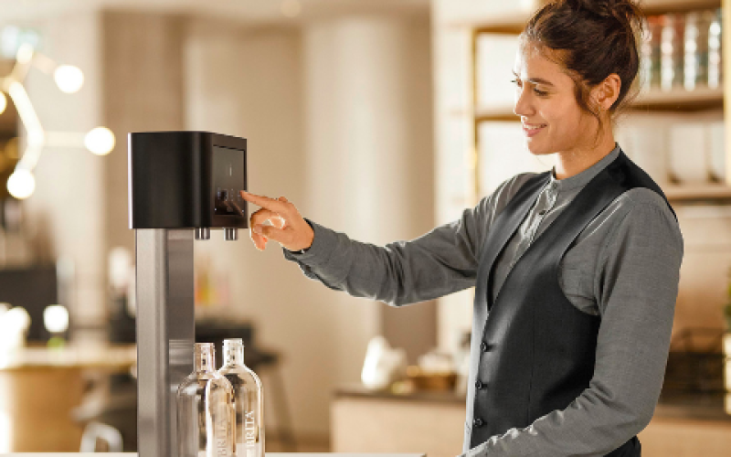 Servicekraft bedient einen Wassersprudler im Restaurant