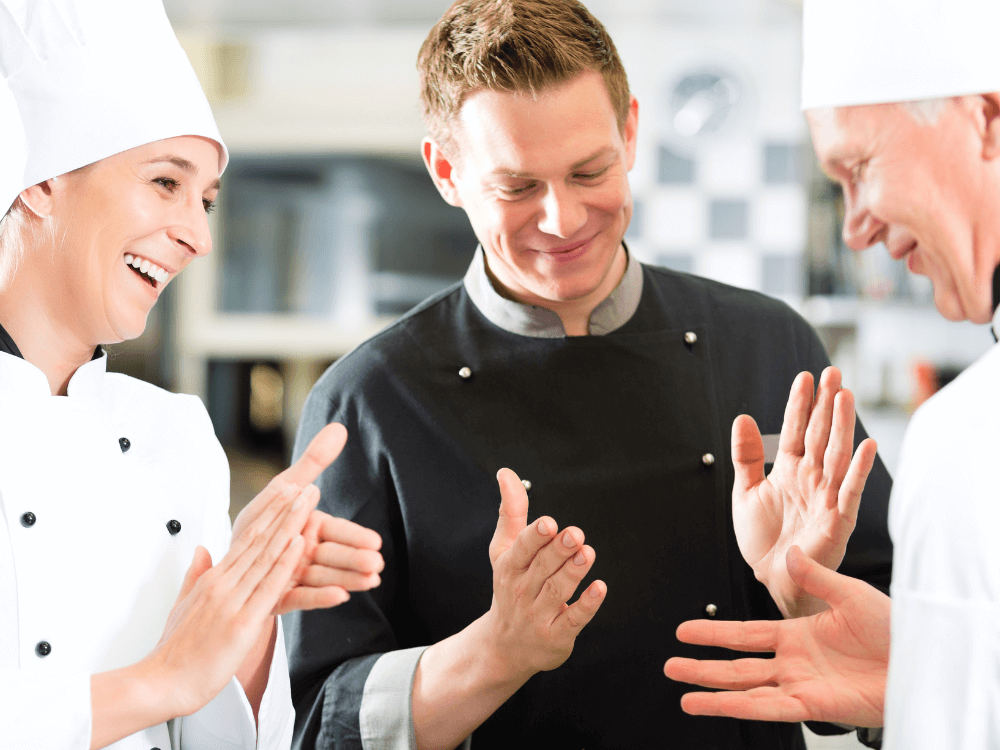 Erfolgreiche Zero Waste Küche: Ein motiviertes Küchenteam freut sich über die optimierten Prozesse und die gemeinsame Reduzierung von Speiseabfällen im Betrieb.